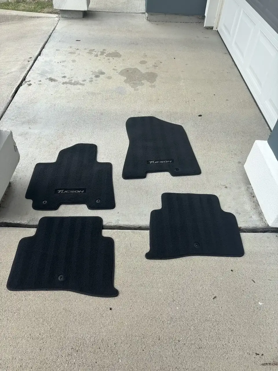 Four cleaned floor mats laid out to dry on a driveway