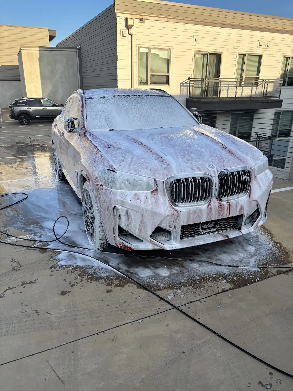 Sedan covered in wash foam during an exterior detail