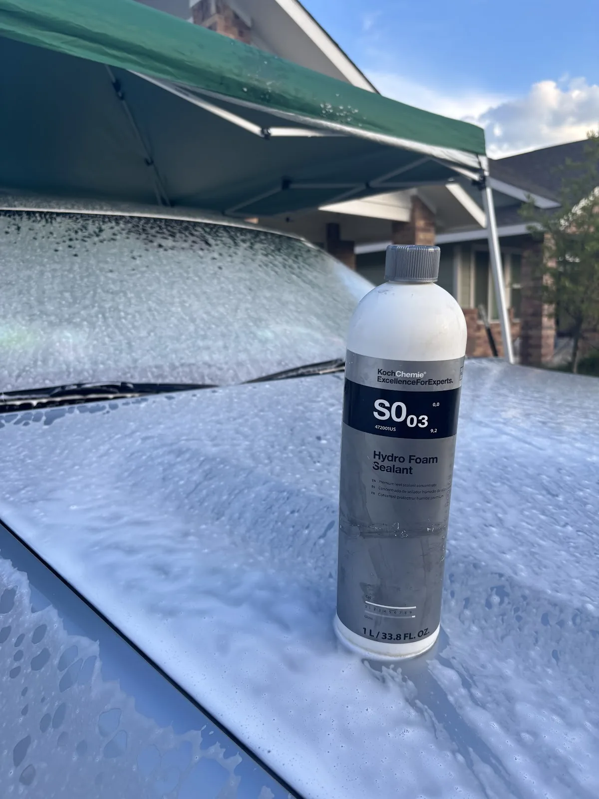Bottle of hydro foam sealant resting on a soapy vehicle hood