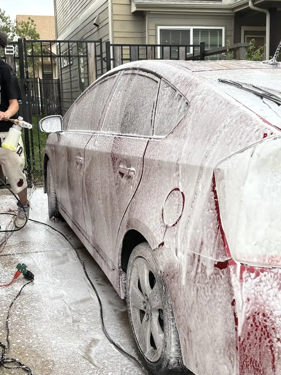 Sedan covered in wash foam on a driveway