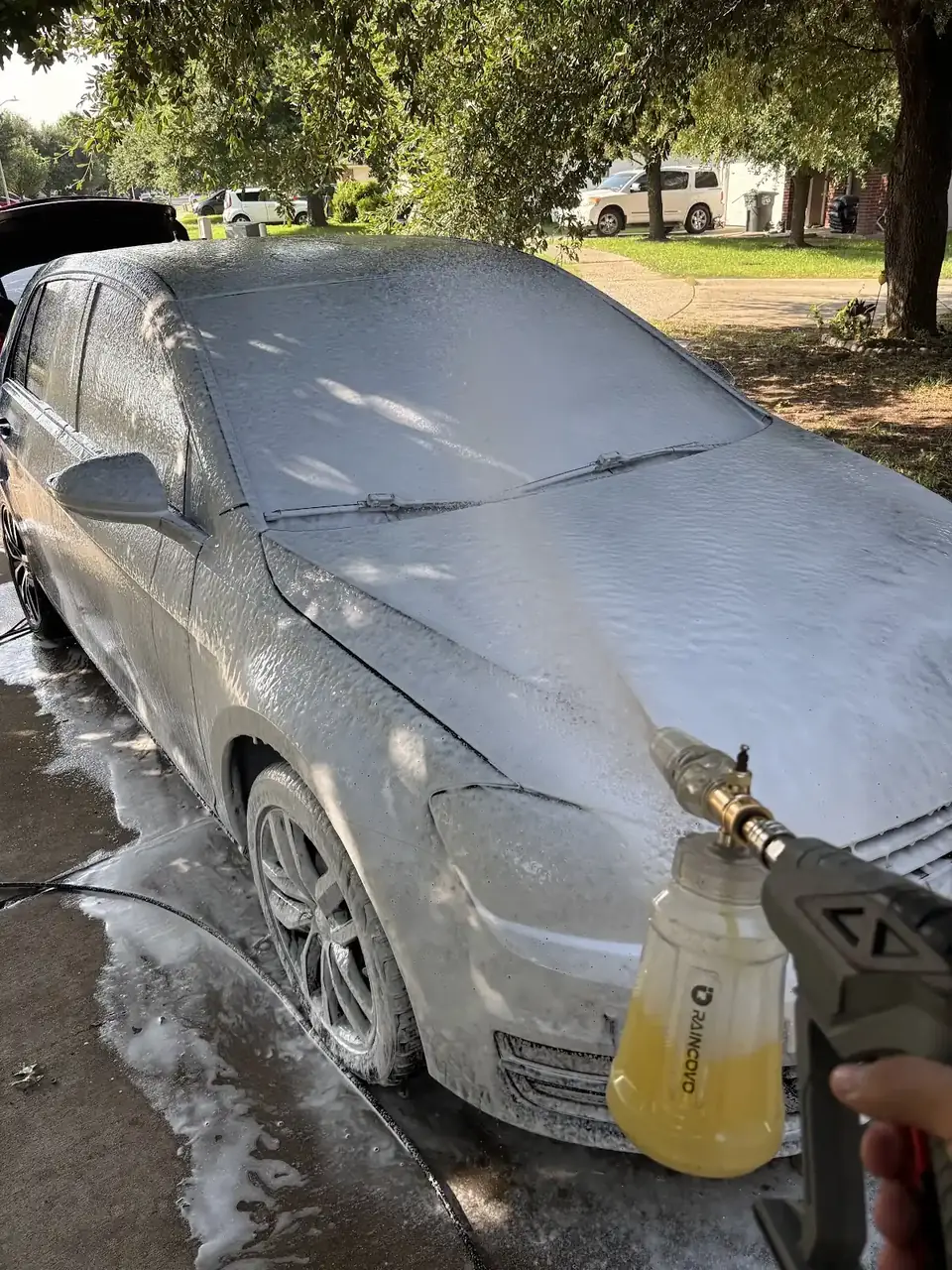 Sedan being rinsed with a foam cannon during a mobile wash