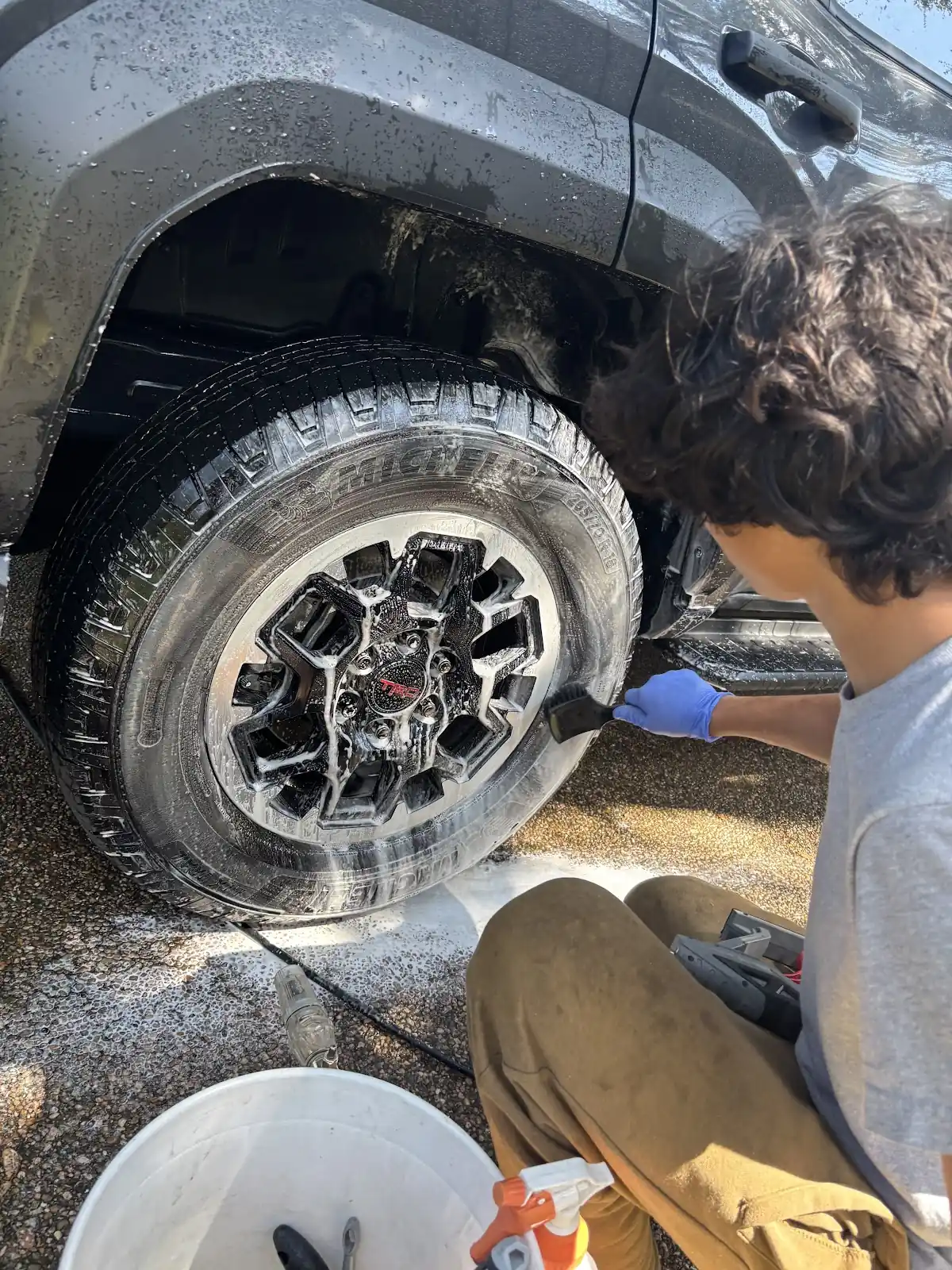 Detailer cleaning a truck wheel with a brush
